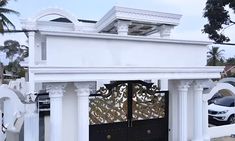 a white house with an ornate gate and car parked in the driveway