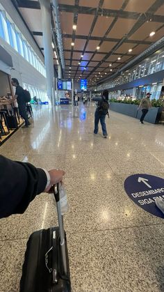 a person pulling a luggage bag through an airport with people walking by in the background