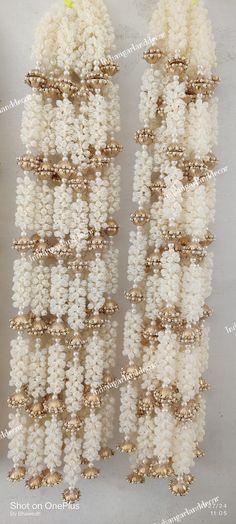 several white and gold beads hanging from the side of each other on a gray surface