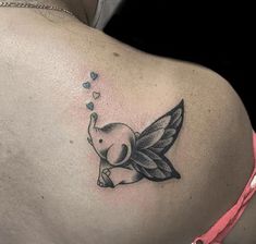 the back of a woman's shoulder with an elephant and hearts tattoo on it