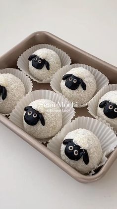 six cupcakes with white frosting and black sheep on them in a tray