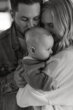 a man and woman holding a baby in their arms