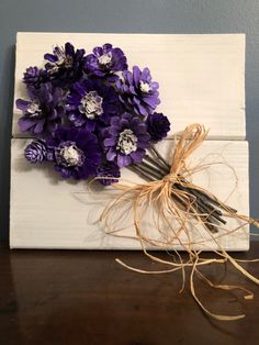 purple flowers are placed on top of a white piece of wood, tied with twine