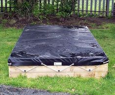 a mattress sitting on top of a wooden box in the middle of some grass next to a fence