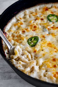 a skillet filled with macaroni and cheese topped with green bell peppers on the side