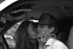 a young man and woman kissing in the back seat of a car while sitting next to each other