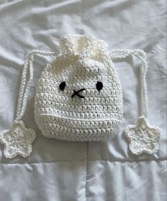 a white crocheted bag sitting on top of a bed next to a pillow