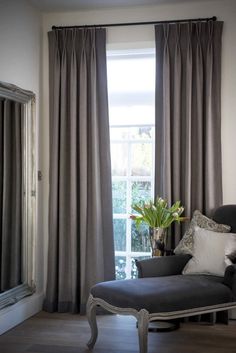 a living room filled with furniture and a window covered in gray drapes next to a mirror