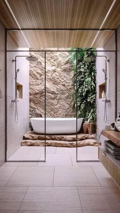 a bathroom with a stone wall and tub in the middle, surrounded by greenery