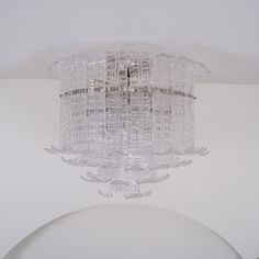 a glass chandelier hanging from the ceiling in a room with white walls and flooring