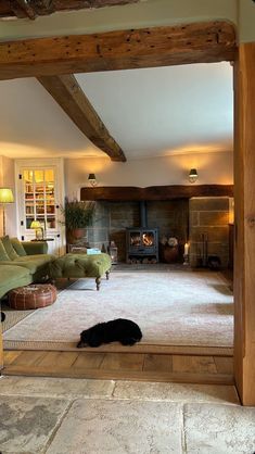 a dog laying on the floor in front of a living room with fireplace and couches