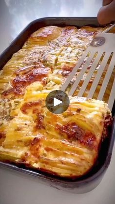 someone is grating cheese on top of a casserole dish with a spatula