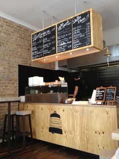 a restaurant with menus hanging from the ceiling and wooden counter tops, along with stools