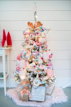 a white christmas tree decorated with pink and gold ornaments, teddy bears and other decorations