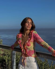 a woman leaning on a rail near the ocean