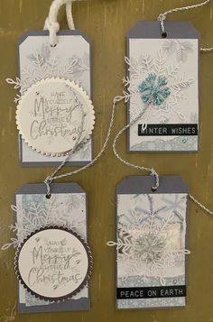 three tags with snowflakes on them hanging from string and some paper attached to the strings