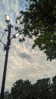 a street light sitting on the side of a pole under a cloudy blue sky with wispy clouds