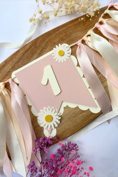 a pink and white birthday card with daisies on the front, next to some flowers