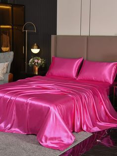 a bed covered in pink sheets and pillows