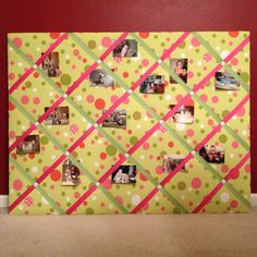 a bulletin board with pictures on it in front of a red wall and carpeted floor