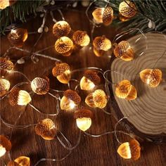 christmas lights on a wooden table next to a pine cone and fir tree branch with needles