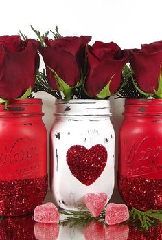 three mason jars with red roses in them and hearts painted on the lids are sitting next to each other