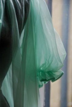 a green bag hanging on the side of a building with sheer fabric covering it's sides