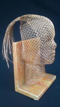 a wire mesh head sculpture on a marble base