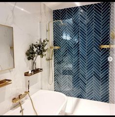 a white bath tub sitting next to a shower with a blue tiled wall behind it