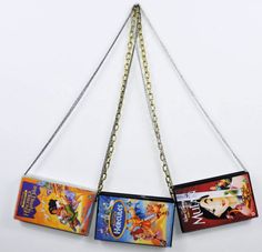 three disney princess purses hanging from chains on a white wall in the shape of an arrow