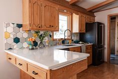 a kitchen with wooden cabinets and white counter tops, an island in front of the sink