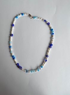 Introducing our stunning handmade beaded necklace, featuring beautiful look-alike water pearls and blue millefiori beads for a touch of elegance and style. This necklace is perfect for dressing up any outfit or adding a pop of color to your everyday look. The crewneck style sits comfortably around your neck, making it a versatile piece that you'll love to wear time and time again. 💙 CARE INSTRUCTIONS: Please handle with care and avoid exposing to water or harsh chemicals to ensure the longevity Millefiori Beads, Beaded Designs, Handmade Beaded Necklace, Crewneck Style, Handmade Beaded Necklaces, Necklace White, Water Pearls, Look Alike, Bead Designs