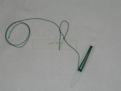 a pen is laying on the ground next to a white card with a green cord