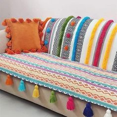 a couch with colorful pillows and tassels on it