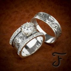 two wedding rings sitting next to each other on top of a brown surface with the letter f