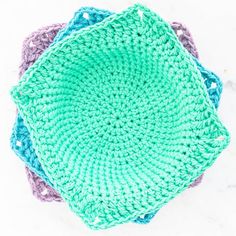 three crocheted dishcloths sitting on top of each other in different colors