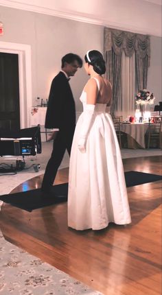 a man and woman in formal wear standing next to each other on a wooden floor