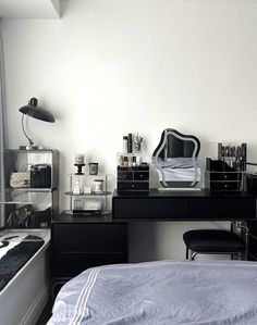 a black and white bedroom with a bed, desk, mirror and other items on it