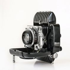 an old fashioned camera sitting on top of a metal stand with a lens attached to it