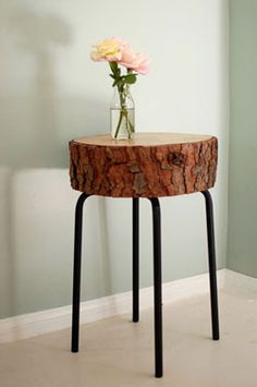 a vase with flowers sitting on top of a wooden table next to a white wall