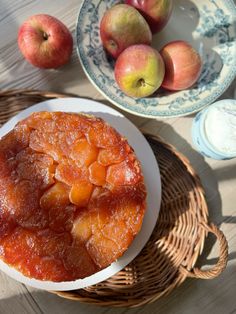 an apple pie sitting on top of a white plate next to two bowls filled with apples