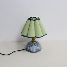 a lamp that is sitting on top of a white table next to a black cord