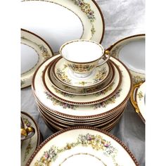 a table topped with lots of white and gold plates covered in floral designs on top of each other