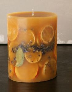 a candle that is sitting on a table with some oranges and lavender around it