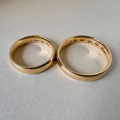 two gold wedding rings with words written on them