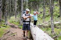 a man and child standing on a log in the woods