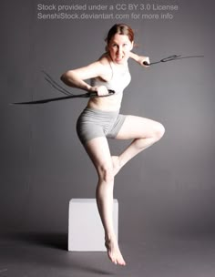 the woman is posing with her legs spread out and tied up to one side, while holding two whip cords in both hands