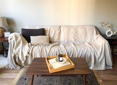 a living room with a couch, coffee table and rugs on the floor in front of it