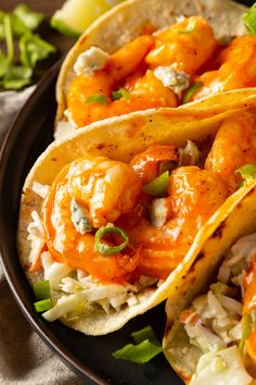 three shrimp tacos on a plate with cole slaw