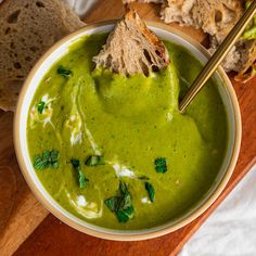 a bowl of green soup with bread on the side